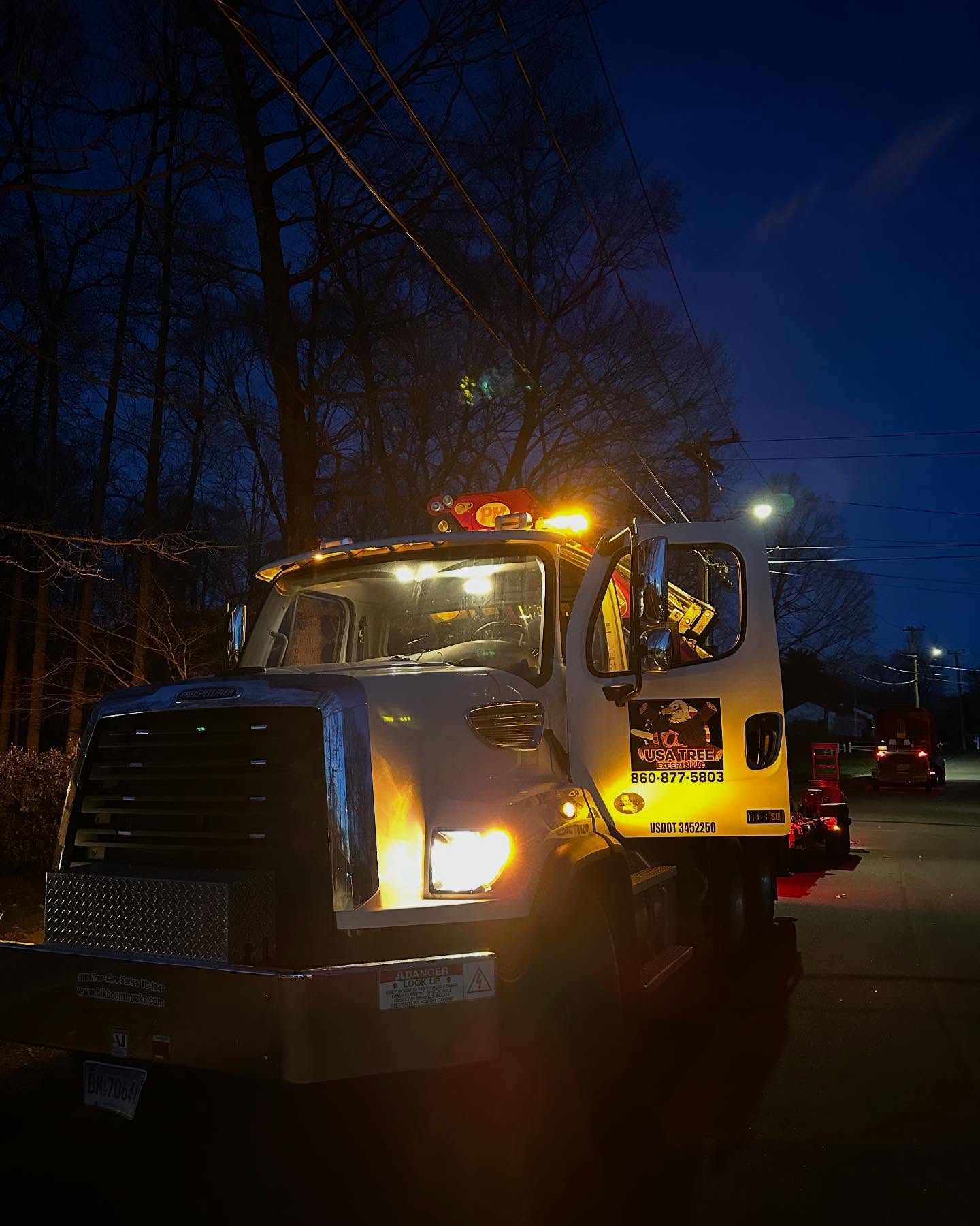 Nightwork Berlin USA Tree Experts service truck at night with yellow hazard lights flashing during an emergency tree removal call in Connecticut.
